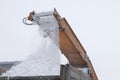 Winter. Close-up of falling snowballs from a snowplow and into a truck body. Snow removal on the streets. Municipal urban road