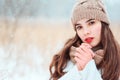 winter close up portrait of beautiful young woman in knitted hat and sweater walking outdoor under snowfall.