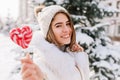 Winter closeup portrait charming joyful young woman in sunny winter morning with pink lollypop street. White warm woolen Royalty Free Stock Photo