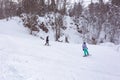 Winter cloudy day, winter sports lovers are engaged in their favorite hobby of conquering the slopes on the mountain slope in the