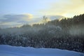 Winter colorful landscape at sunset. Fog over the forest. The road is covered with snow. Deep snowdrifts. It feels cold. Royalty Free Stock Photo