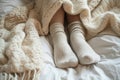 Winter comfort legs in leggings and wool socks peeking from blanket