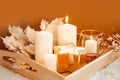 Winter composition. Burning candles and golden maple leaves on a beige background. Selective focus.