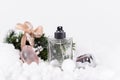 Winter composition of Christmas tree branches with a rustic bow, artificial snow and snow balls and bottles of perfume, Royalty Free Stock Photo