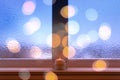 Frosted window, burning candle and bokeh lights Royalty Free Stock Photo