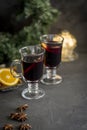 Winter composition. Mulled wine in glasses at black background. Fir wreath, lights, tray with orange, cinnamon, nuts and spices Royalty Free Stock Photo