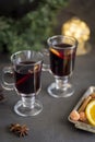 Winter composition. Mulled wine in glasses at black background. Fir wreath, lights, tray with orange, cinnamon, nuts and spices Royalty Free Stock Photo