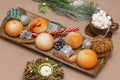 Winter composition. Tangerines in snow, candies, candle and coffee with marshmallows on the table. Close-up, selective focus