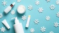 Winter cosmetic products set on blue background. Lipstick, cream jar, pump bottle, tube package mockup and snowflakes. Flat lay, Royalty Free Stock Photo