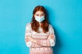 Winter, covid-19 and quarantine concept. Skeptical redhead girl in sweater and medical mask, cross arms on chest and