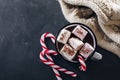 Winter cozy beverage. Glass with hot chocolate with marshmallow, candy cane, cozy warm scarf on dark blue background. Top view Royalty Free Stock Photo