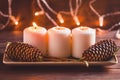 Winter cozy decoration with white burning candles on a wooden festive table and blurrred lights Royalty Free Stock Photo