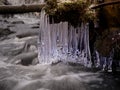 Winter creek with icicles above freeze mountain stream. Winter season Royalty Free Stock Photo