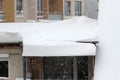 Winter. Dangerous snow falls from the roofs of the buildings. Winter with heavy snowfall. Icy roofs. Dangerous icicles above road.