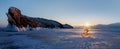 Winter dawn landscape on Lake Baikal. Silhouette of a cyclist in the rays of the rising sun against the backdrop of a huge rock. Royalty Free Stock Photo