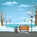 Winter day park. Snow covered wooden bench, trash bin and street lamp with a frozen lake. Royalty Free Stock Photo