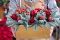 Winter decor. Beautiful flower arrangement of red roses, natural sprigs of blue spruce and Christmas berry holly or ilex twigs, Royalty Free Stock Photo