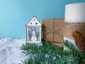 Winter decorated lantern with snowman next to presents, white candle and fir tree branch