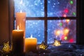 Winter decoration with candles near the snow-covered window Royalty Free Stock Photo