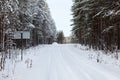 Winter dirt road covered with snow, coniferous forest. Russia