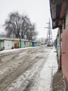 Winter dirty broken road in a garage cooperative. Gray depressing moody winter Royalty Free Stock Photo