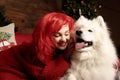 Winter dog holiday and Christmas. A girl in a knitted sweater and with red hair with a pet in the studio. Christmas Royalty Free Stock Photo
