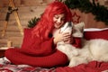 Winter dog holiday and Christmas. A girl in a knitted sweater and with red hair with a pet in the studio. Christmas Royalty Free Stock Photo