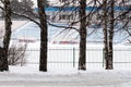 Winter empty stadium. Football field and seats for the teams spectators covered with snow. Sports seasons.