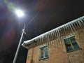 winter evening icicles hanging from the roof in the light of a lantern Royalty Free Stock Photo