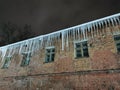 winter evening icicles hanging from the roof in the light of a lantern Royalty Free Stock Photo