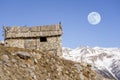 Winter evening landscape in french Alps. Old stone abandoned house on the mountain. Full moon on the sky Royalty Free Stock Photo