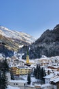 Winter evening in ski resort Ischgl in Tyrol Alps. Snow covered town is in shadows, but mountains are sunlit