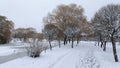 In winter everything is covered with snow, and the water canal in the city park is covered with ice. There is a walkway with peopl Royalty Free Stock Photo