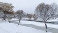 In winter, everything is covered with snow, and the water channel in the city park is partially covered with ice. Trees are reflec Royalty Free Stock Photo