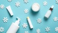 Winter face care cosmetic products. Moisturizer cream, serum, lipstick, tube, pump bottle, snowflakes on blue background.Flat lay Royalty Free Stock Photo