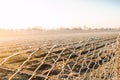 Winter farm field through view a mesh fence. Beautiful sunrise in countryside. Frost on fence grate, frosty cold. Property fencing Royalty Free Stock Photo