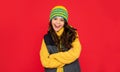 winter fashion. emotional happy kid with curly hair in hat. teen girl on red background.