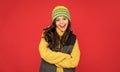 winter fashion. emotional happy kid with curly hair in hat. teen girl on red background.