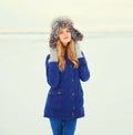 Winter fashion portrait smiling woman wearing fur hat over snow Royalty Free Stock Photo