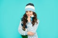 winter fashion. positive kid with curly hair in hat and scarf. teen girl on blue background.