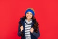 winter fashion. positive kid with curly hair in hat. teen girl on red background.