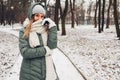 Winter fashion. Young woman wearing long green coat with scarf, hat, mittens in snowy park Royalty Free Stock Photo