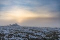 Winter field at sunset with icy grass, the sun behind low clouds Royalty Free Stock Photo