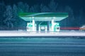 Winter filling station at night with long light tracks from the headlights of passing cars