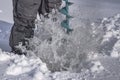 Winter fishing concept. Fisherman in action. Some one is making the hole in snowy ice at lake by ice