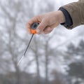 Winter fishing concept. Hand of fisherman with specialised rod above snowy ice