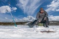 Winter fishing concept. Fisherman in action. Catching perch fish from snowy ice at lake above troop of fish. Double view under