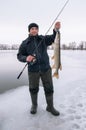 Winter fishing concept. Fisherman with pike fish trophy and spinning tackle