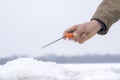 Winter fishing concept. Hand of fisherman with specialised rod above snowy ice