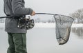 Winter fishing. Fisherman with pike fish in landing net Royalty Free Stock Photo